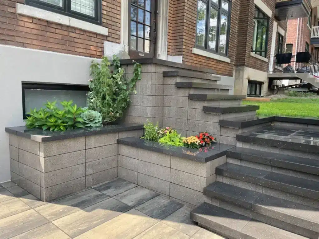 Escalier moderne en pavé uni avec jardinières fleuries.